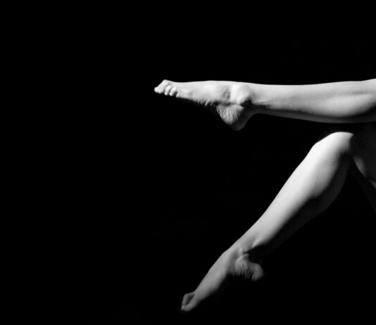 다리 통증 완화 운동법: 필라테스로 튼튼한 다리 만들기 a naked woman laying on her back in the dark