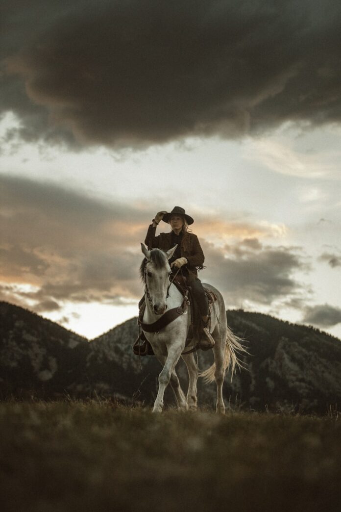 Photo by Taylor Brandon 2 men riding horses on grass field during daytime
