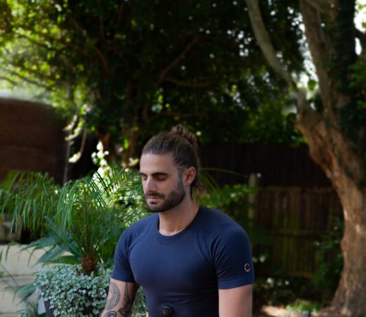 건강을 지키는 비법 a man sitting on a yoga mat in the middle of a garden