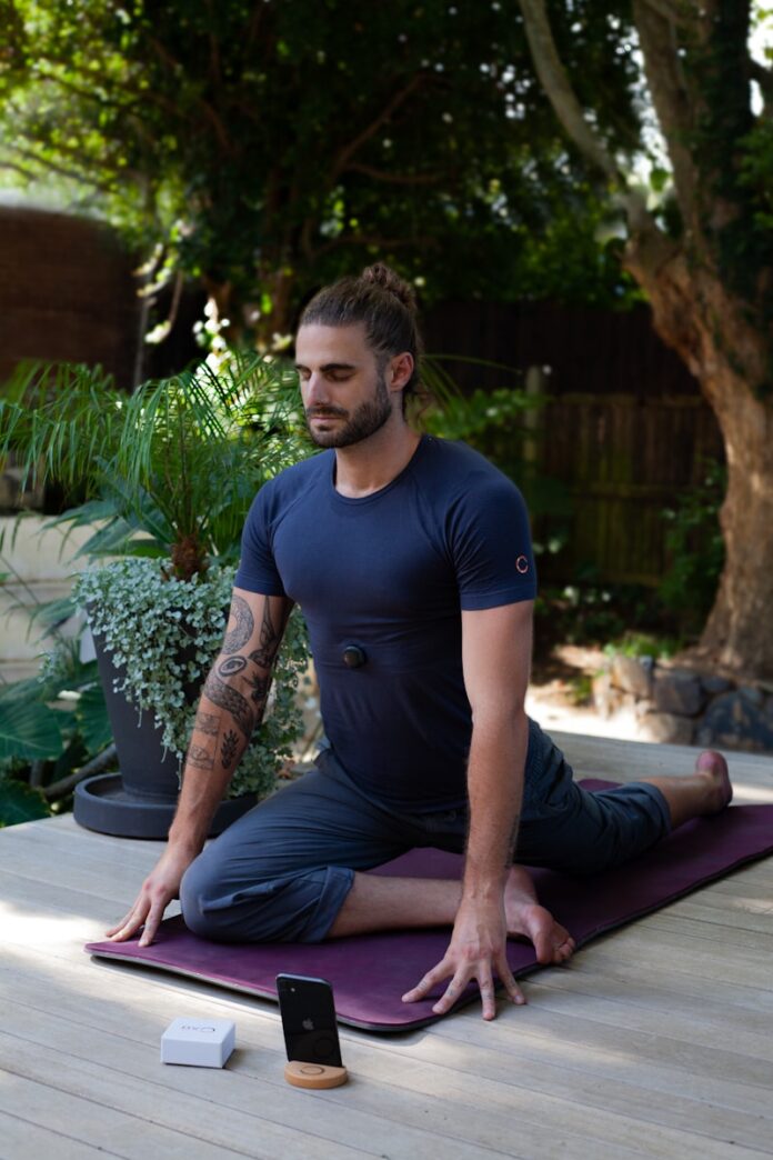 Photo by Angelina Sarycheva a man sitting on a yoga mat in the middle of a garden