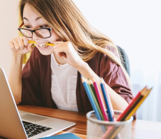 만성 스트레스와 코르티솔 수치: 건강에 미치는 장기적 영향 woman biting pencil while sitting on chair in front of computer during daytime