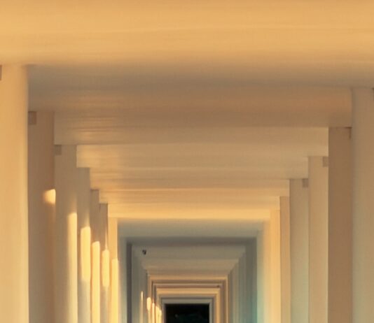 ‘마이크로 운동’이 바꾸는 우리의 하루, 짧고 자주 움직이기가 건강 열쇠 Woman walks down a sunlit colonnade hallway.