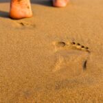 맨발 걷기(어싱) 열풍: 땅과 소통하는 시간, 정말 건강에 도움이 될까? Footprints on a sandy beach leading away