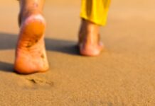 맨발 걷기(어싱) 열풍: 땅과 소통하는 시간, 정말 건강에 도움이 될까? Footprints on a sandy beach leading away