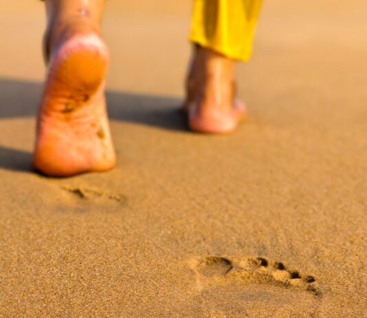 맨발 걷기(어싱) 열풍: 땅과 소통하는 시간, 정말 건강에 도움이 될까? Footprints on a sandy beach leading away