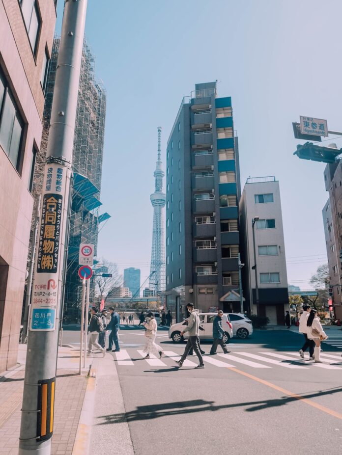 People crossing street with tall tower in background