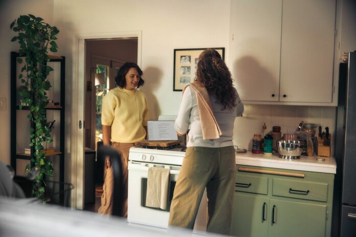 Photo by Microsoft Copilot Two women talking in a kitchen while cooking