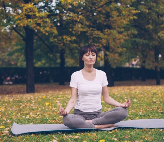집에서도 손쉽게, ‘마음챙김 운동’ 바람… 실생활 루틴으로 스트레스 줄이기 Woman meditating in a park during autumn.